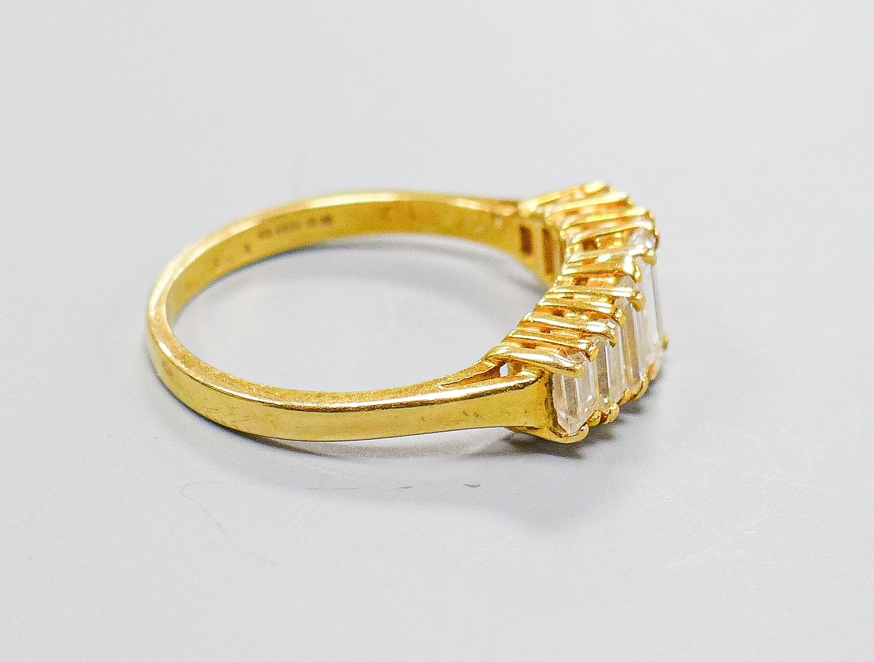 A modern 18ct gold and graduated seven stone baguette cut diamond set half hoop ring, size O, gross weight 4.1 grams.